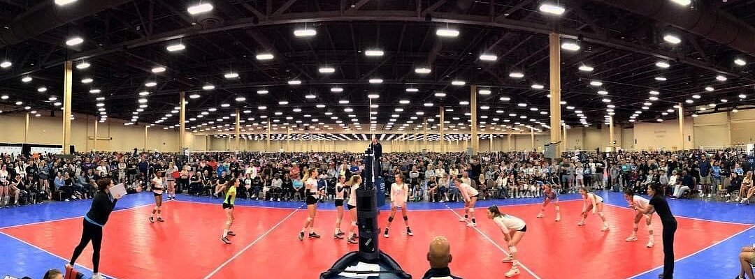Panoramic view of an SCVA tournament court with full bleachers and players in match position inside an arena.